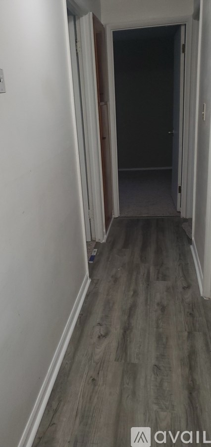 A hallway with a wooden floor and white walls.