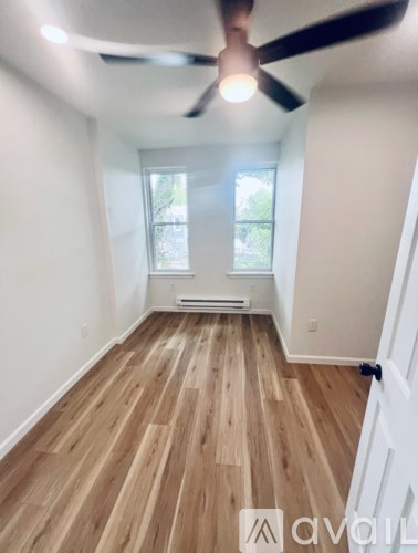 A room with a ceiling fan and wooden flooring.