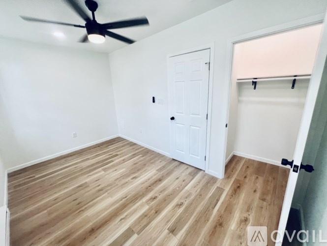 A room with a ceiling fan and wooden flooring.