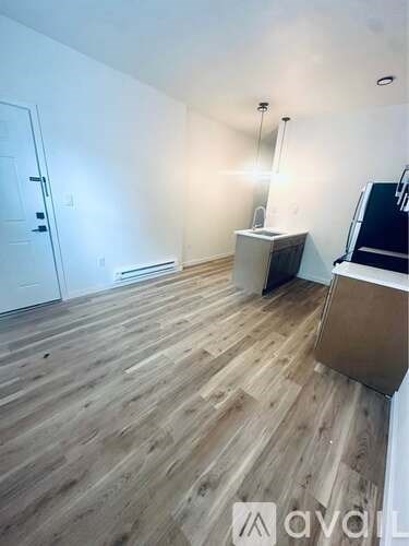 A room with wooden flooring and a white wall.