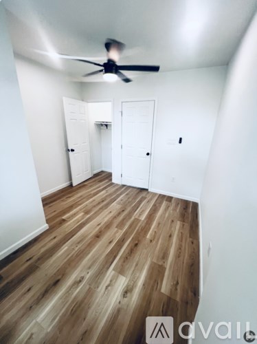 A room with a ceiling fan and wooden flooring.