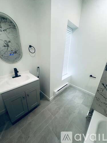 A bathroom with a sink, mirror, and grey cabinets.