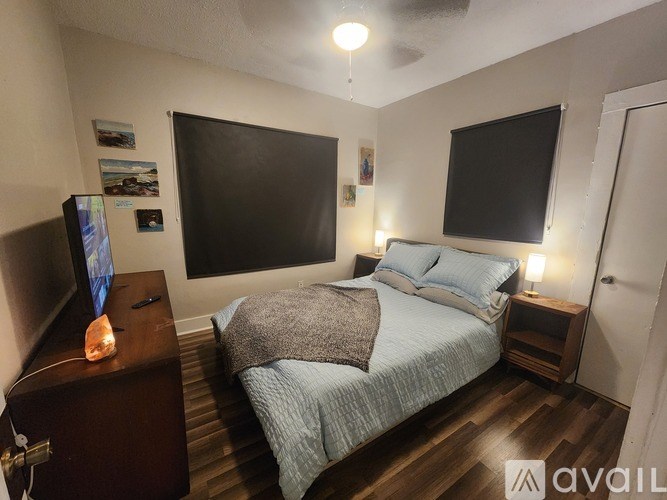 A bedroom with a bed, a television, and a wall-mounted monitor.