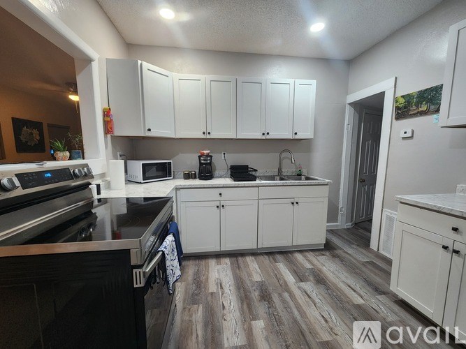 A kitchen with white cabinets and a wooden floor.