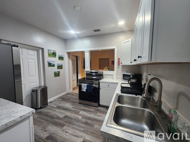 A kitchen with a sink, fridge, and cabinets.