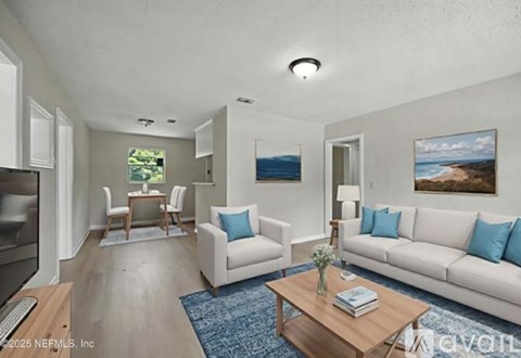 A living room with a white couch, a coffee table, and a painting on the wall.