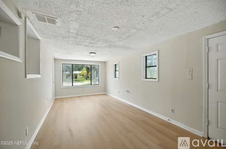 A spacious room with wooden floors and a large window.