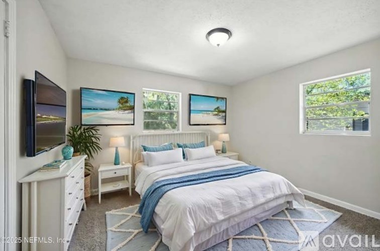 A bedroom with a large bed, a desk with a computer, and a painting on the wall.