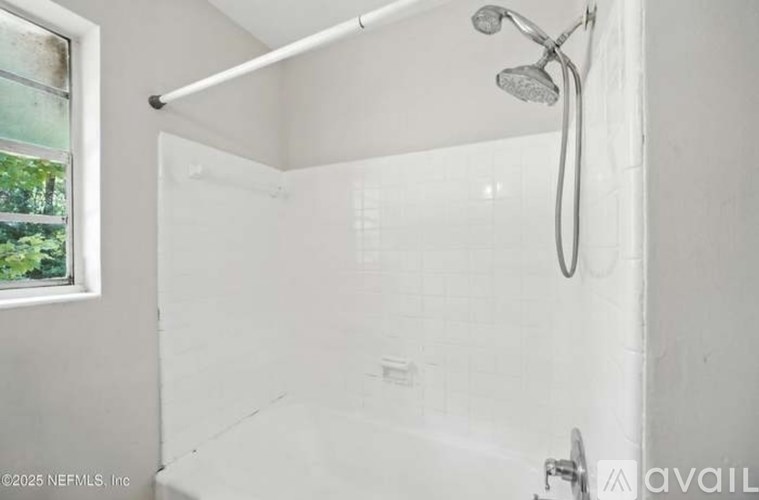 A white bathroom with a shower and a window.