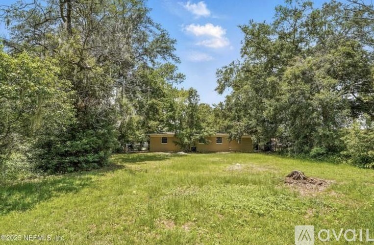 A small building is surrounded by trees and grass in a sunny outdoor setting.