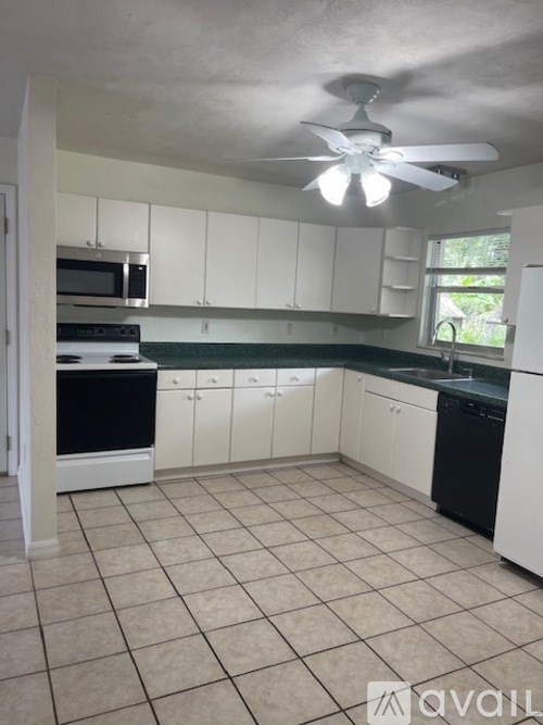 A kitchen with white cabinets and black appliances.