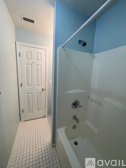 A white door is in a hallway next to a blue wall.