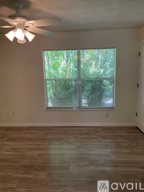 A room with a ceiling fan and a window with blinds.