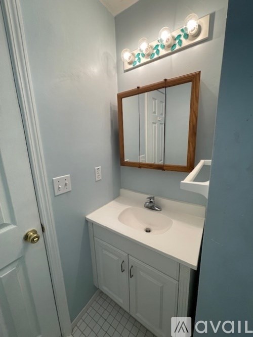 A bathroom with a white sink and a mirror with lights above it.