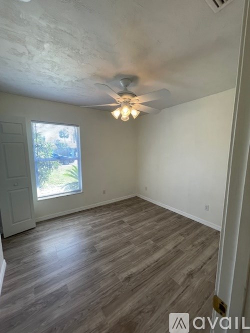 A room with a ceiling fan and wooden flooring.