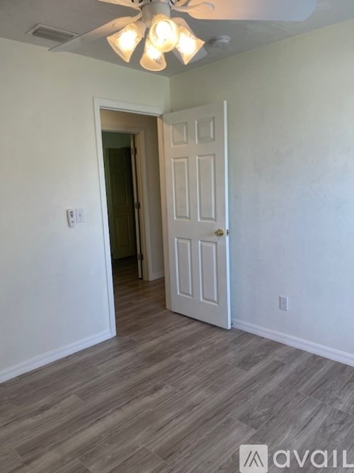 A room with a white door and a ceiling fan with lights.