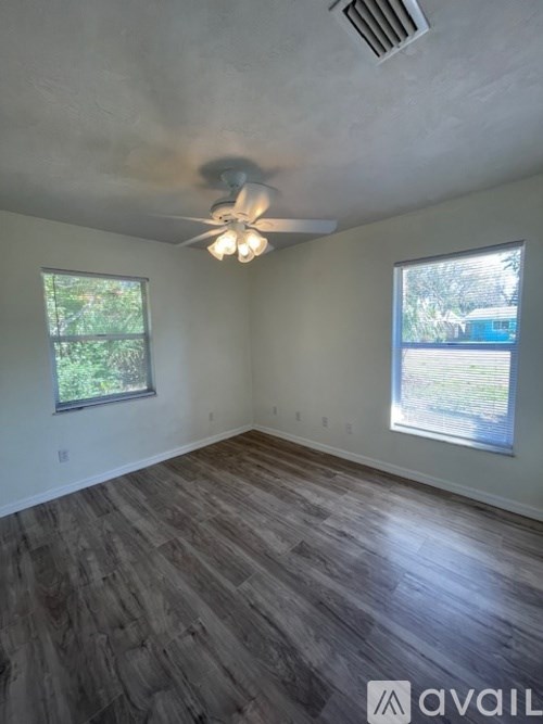 A room with a ceiling fan and two windows.