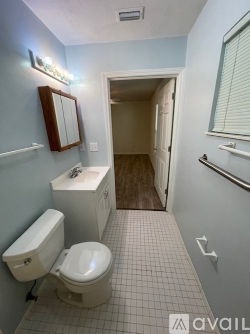 A bathroom with a toilet, sink, and mirror.