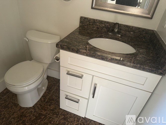 A bathroom with a toilet, sink, and cabinet.