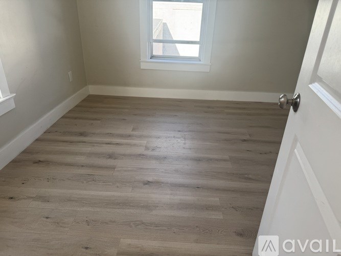 A room with wooden flooring and a window.