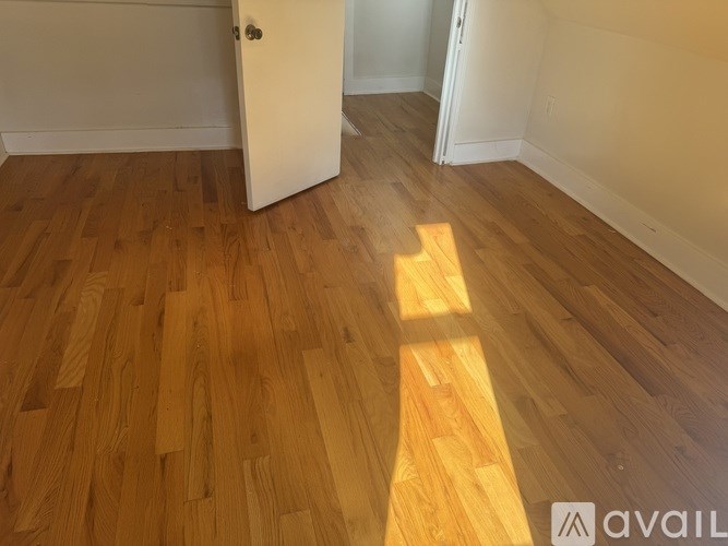 A room with wooden flooring and a door in the background.