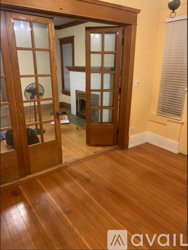 A room with wooden floors and a glass door leading to another room.