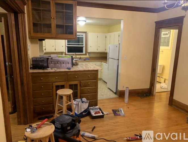 A kitchen with wooden cabinets and a white refrigerator is under renovation.