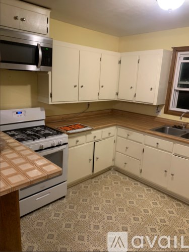 A kitchen with a stove top oven and white cabinets.