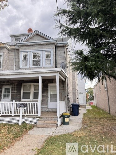 A two-story house with a white porch and a mailbox on the front door.