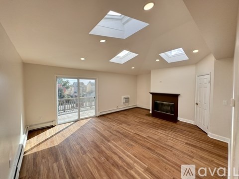 A spacious room with wooden flooring and skylights.