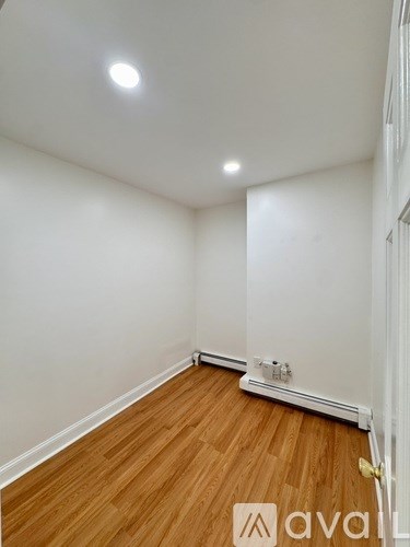 A room with wooden flooring and white walls.