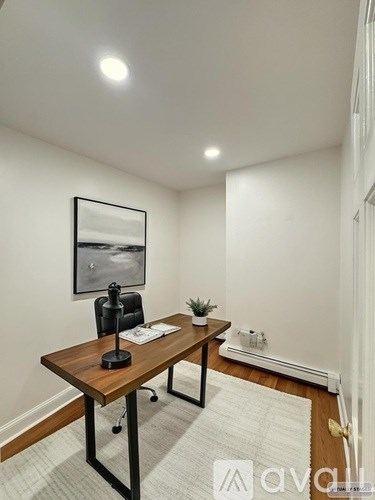 A room with a wooden desk and a black chair.