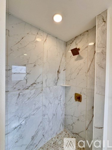 A bathroom with marble walls and a shower.
