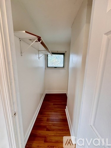 A long hallway with a window and a wooden floor.