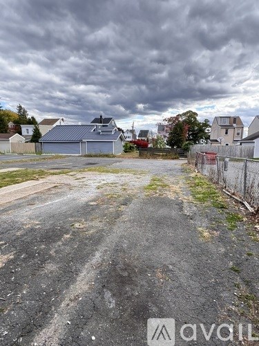 A road with a fence and houses in the background.
