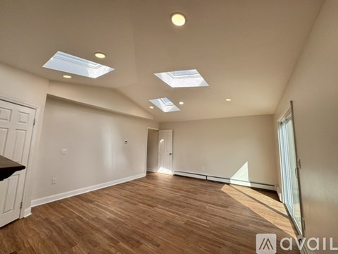 A spacious room with wooden floors and skylights.