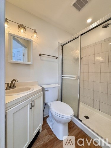 A white bathroom with a toilet, sink, and shower.