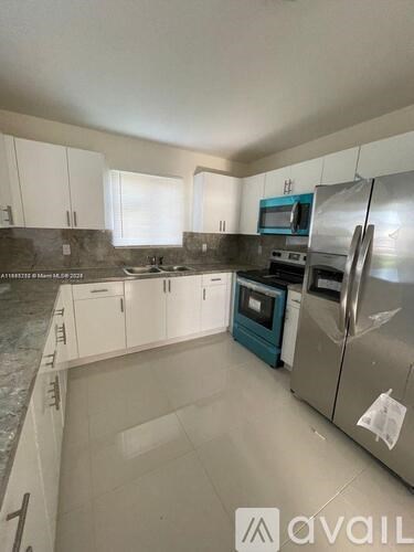 A kitchen with white cabinets and a stainless steel refrigerator.