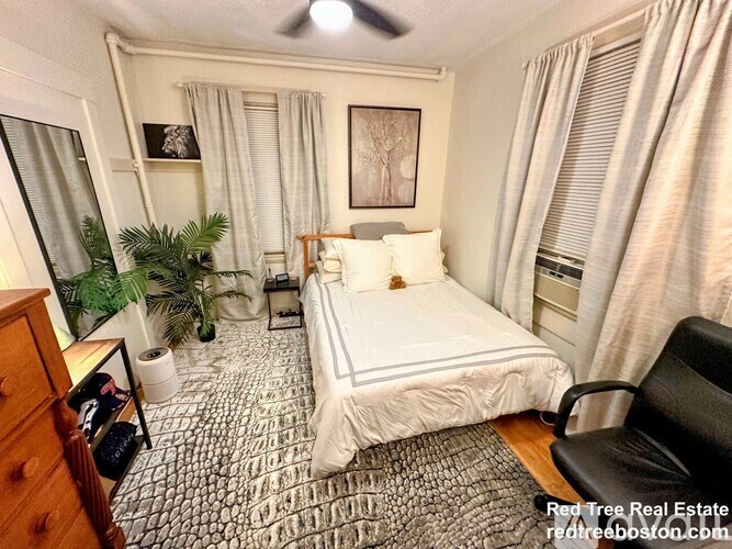 A bedroom with a bed, chair, and potted plant.