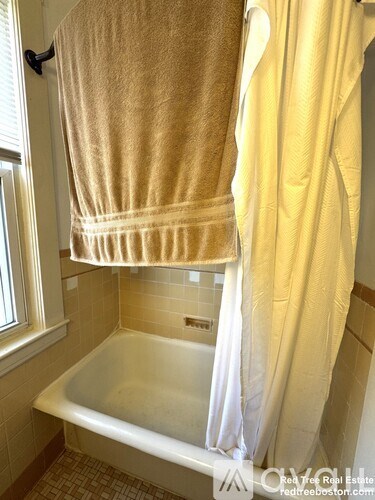 A white bathtub with a towel hanging over the side.