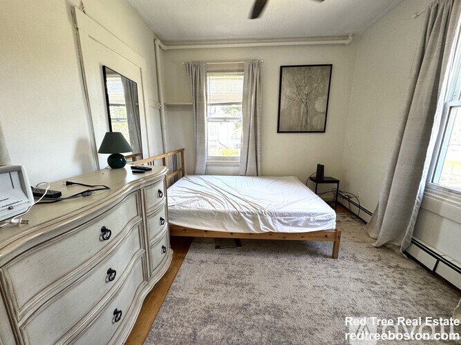 A bedroom with a bed, dresser, and window.