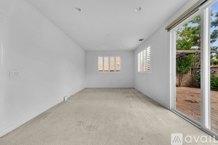 A room with a carpeted floor and a window with blinds.