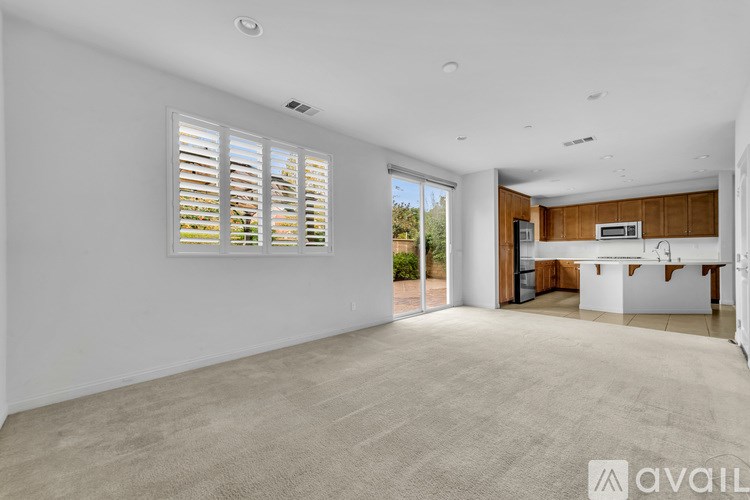 A spacious living room with a kitchen area in the background.