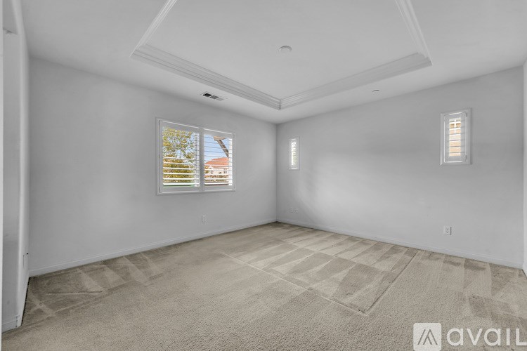 A room with a carpeted floor and a window with blinds.