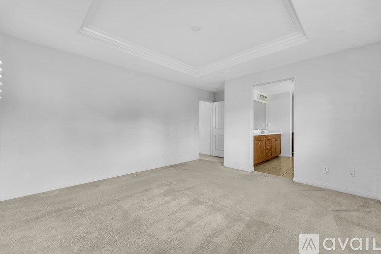 A large empty room with a kitchen area in the background.