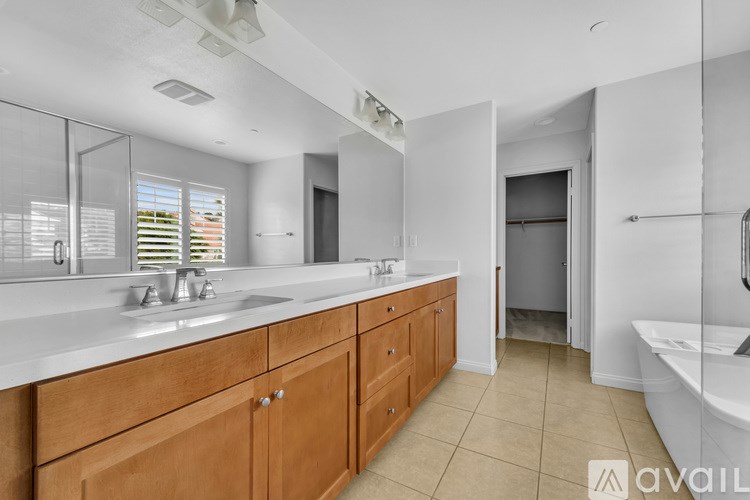 A bathroom with a white sink and wooden cabinets.