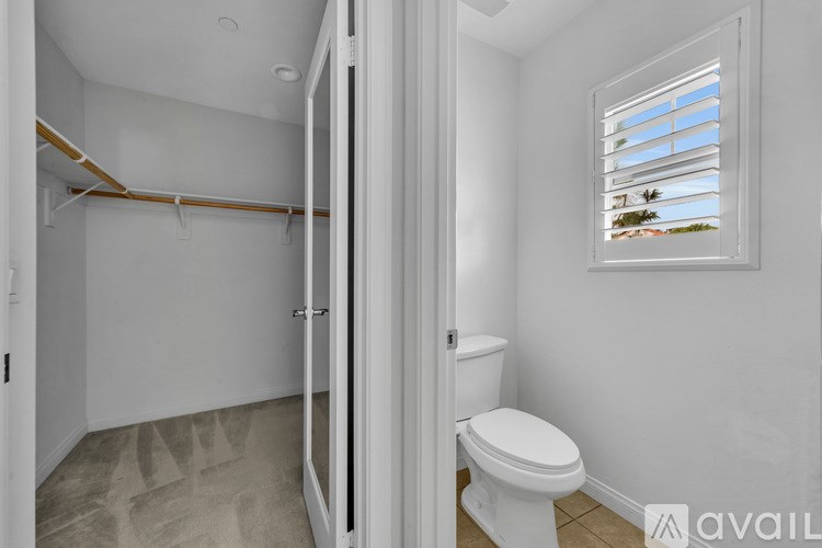 A bathroom with a toilet, a window with blinds, and a walk-in shower.