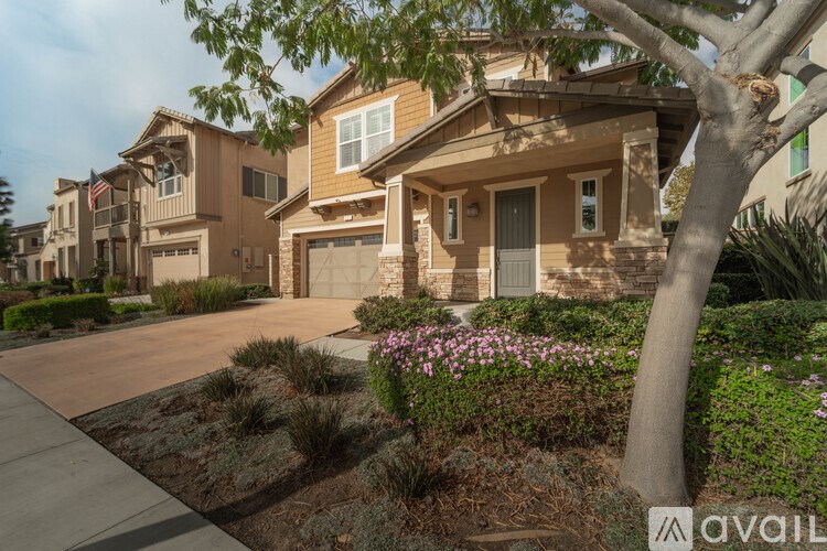 A house with a driveway and a tree in front.