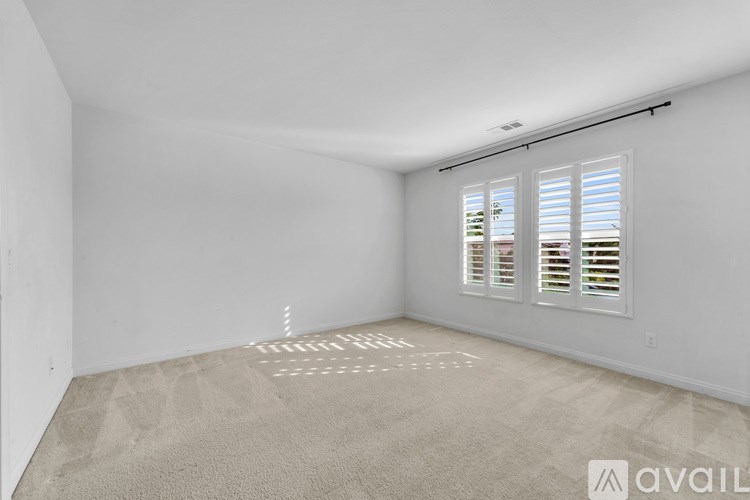 A room with a carpeted floor and a window with blinds.