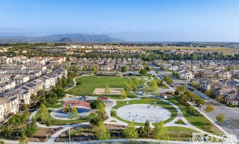 A park with a playground and a basketball court is surrounded by residential buildings.